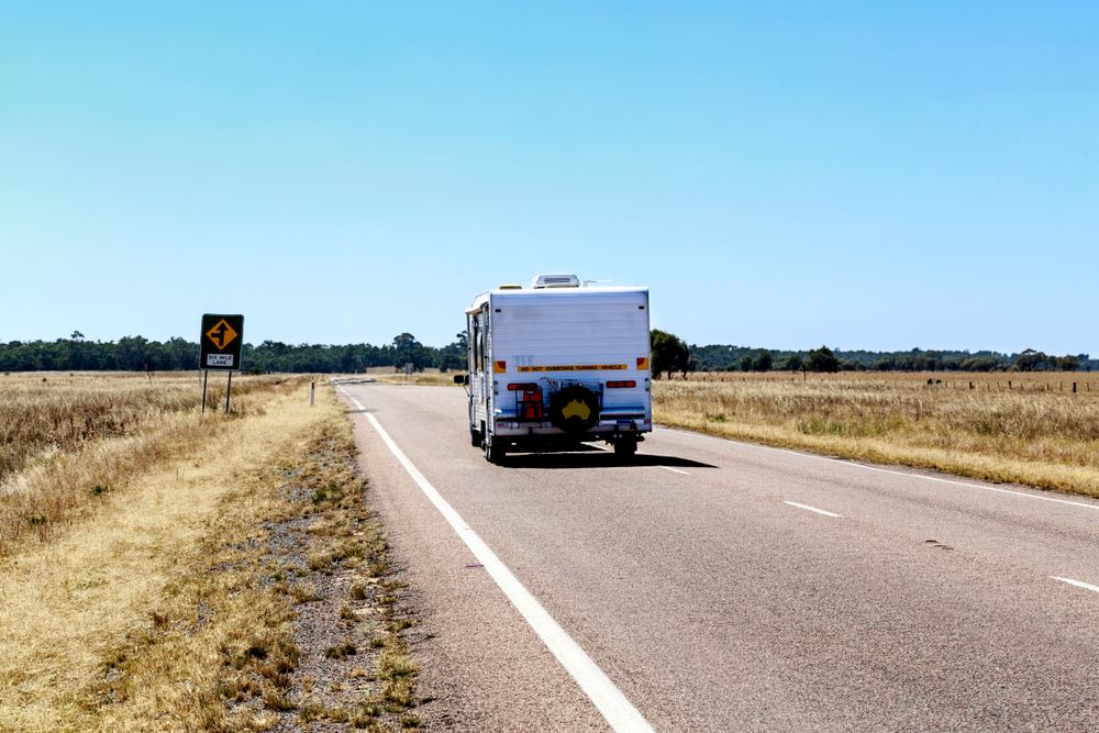 caravan driving away down road in the outback
